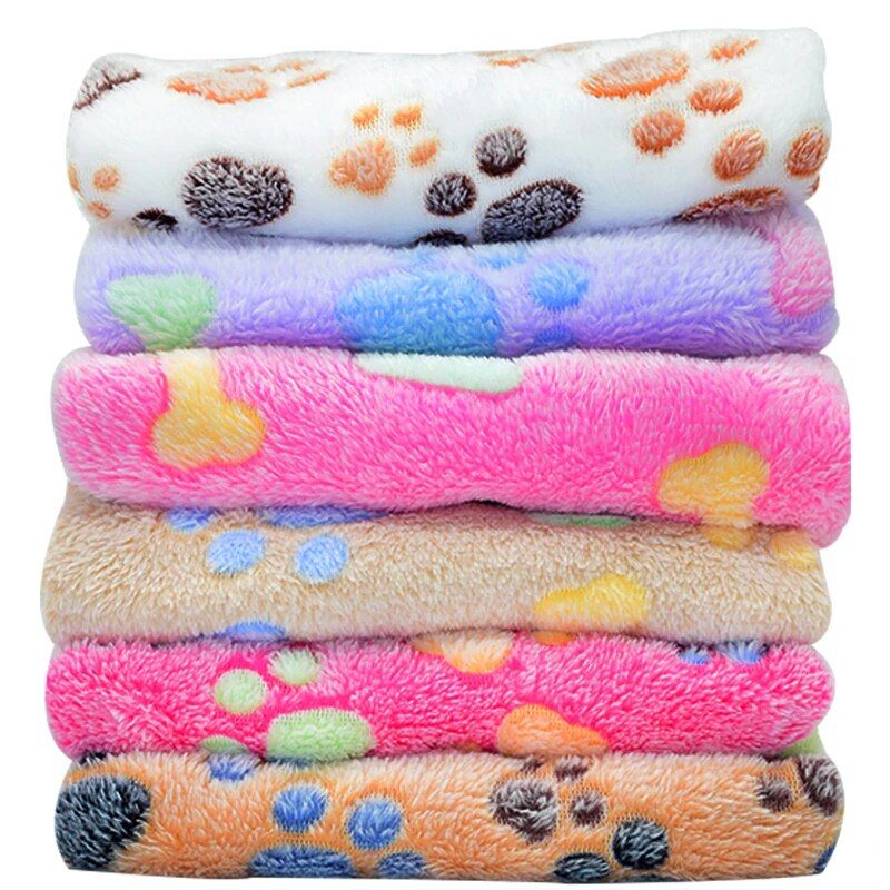 A stack of colorful blankets with various paw print designs is arranged from top to bottom: 11395-6faaeb.jpg, light pink, blue, pink, tan, and orange.